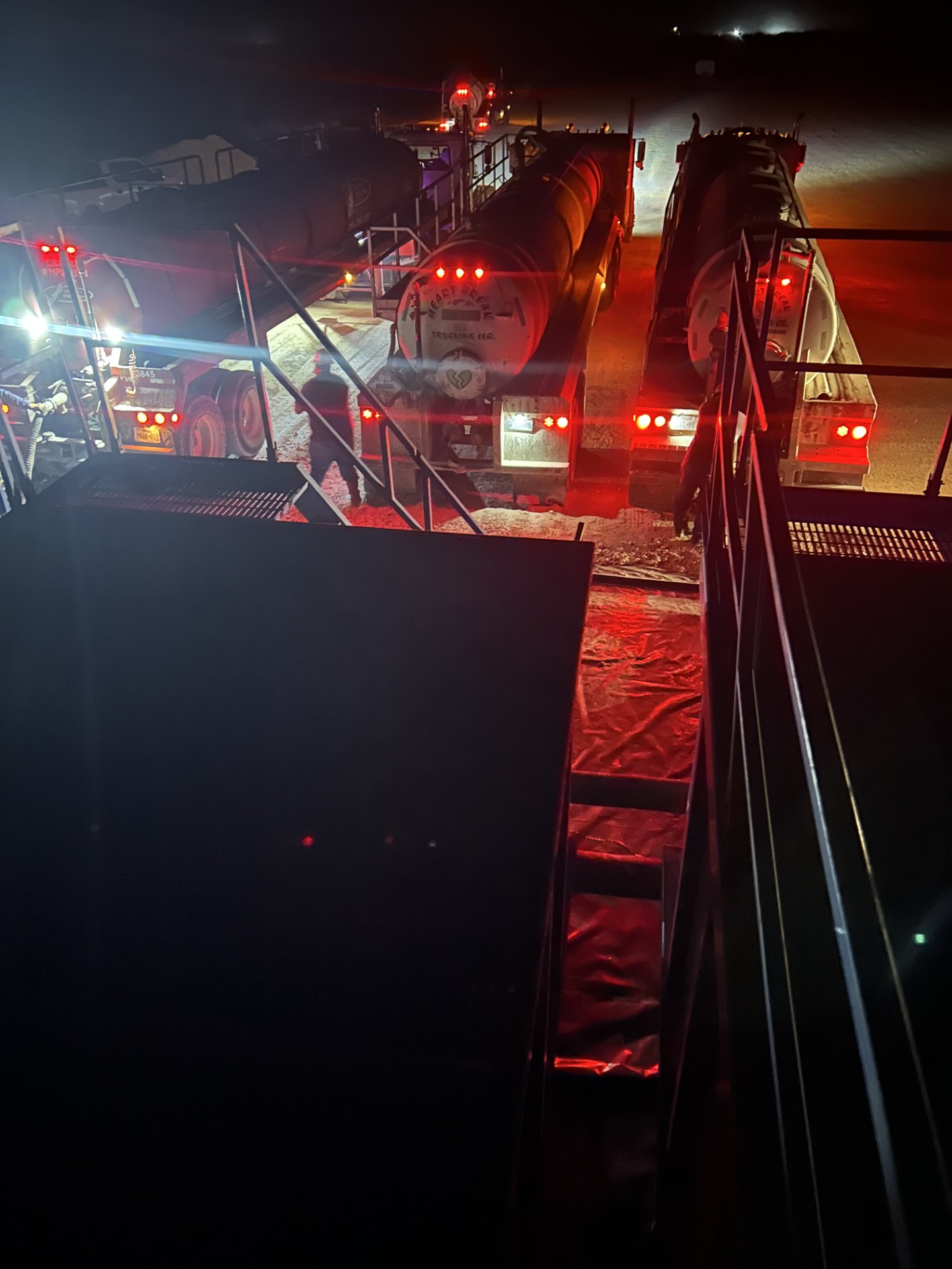 Heartbreak Trucking vacuum trailers lined up on location at night